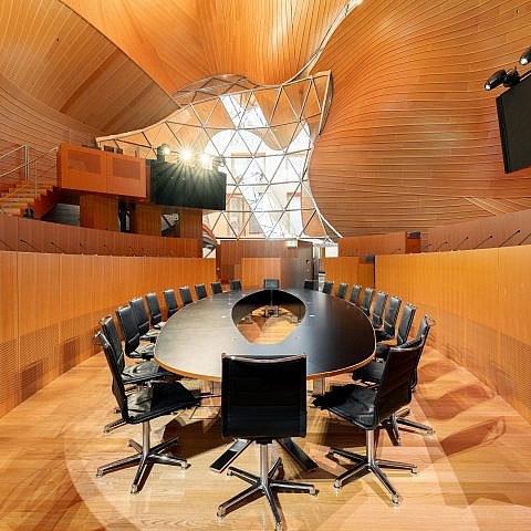 Der ovale Boardroom-Tisch im Plenum der AXICA unter der geschwungenen Holzdecke